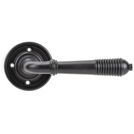 Aged bronze reeded lever door handle on a round rose, showing the reeded grip detail and round rose with fixing holes